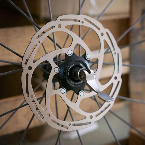 Centerlock 140mm Disc Brake Rotor For MTB And Road Bikes With Beefy High Strength Steel Core And Lightweight Alloy Body 1.8mm Thickness Durable Performance Fits Any Pads Black mounted on wheel with spokes showing rotor design