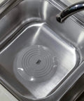Bathtub Drain Stopper 6 Inches Silicone Rubber Plug, Black placed in a stainless steel kitchen sink for blocking drains.