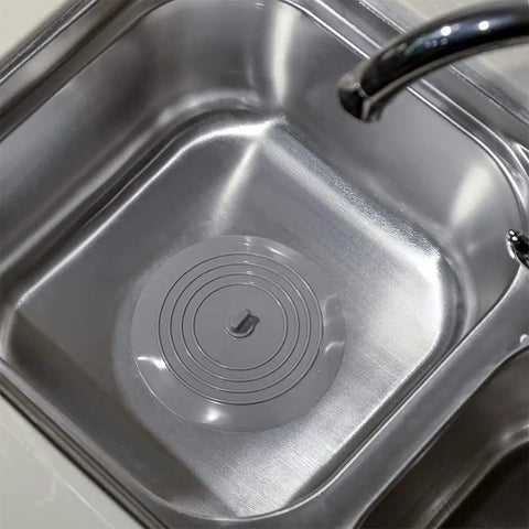 Bathtub Drain Stopper 6 Inches Silicone Rubber Plug, Black placed in a stainless steel kitchen sink for blocking drains.