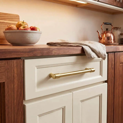 Top Tier Brushed Brass Cabinet Pulls 10 Pack Featuring 96MM Hole Spacing on a kitchen drawer beneath a wooden countertop.