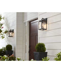 Grandbury Collection 1-Light Clear Glass Farmhouse Outdoor Wall Lantern in Textured Black on porch by wooden door