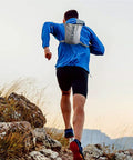 Runner on rocky terrain wearing Lightweight Hydration Vest Backpack With 1.5L Insulated Water Bladder, blue jacket