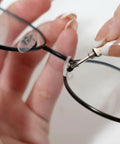 Hand holding eyeglasses while using tool to adjust nose pad, showcasing Complete Eyeglass Repair Kit With 1000 PCS In 32 Slot Blue Case Featuring Rust Proof Stainless Screws Soft Silicone Nose Pads Tweezers And Cloths For Quick No Sweat Fixes To Frames And Shades On The Go.