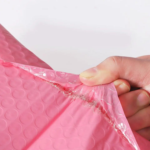 Close-up of hand peeling adhesive strip on Pink Bubble Mailers 60 Pack Self Seal Padded Shipping Bags 11x15cm Adhesive Envelopes