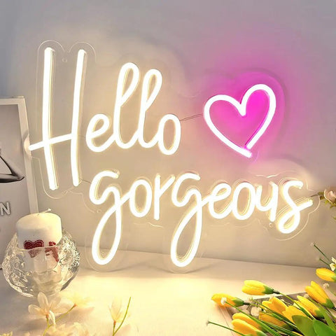 Hello Gorgeous Neon Sign For Girls Bedroom Wall Decor LED Light With Warm White Glow Perfect For Birthday Parties Weddings And Gifts 16.7x12.3 Inches Great Gift Idea displayed on a desk with decorative flowers