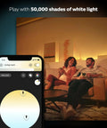 Couple enjoying warm white light from White Ambiance BR30 LED Smart Bulbs with Bluetooth control, phone app interface shown.