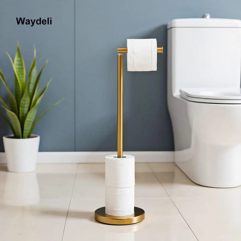 Gold freestanding toilet paper holder stand with reserve for four rolls, sturdy base, next to a white toilet and potted plant.