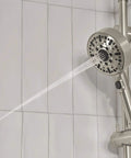 Precept Slide Bar With Brushed Nickel Finish shower system, showing water spray from the hand shower on a tiled wall