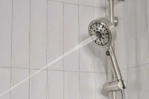 Precept Slide Bar With Brushed Nickel Finish shower system, showing water spray from the hand shower on a tiled wall