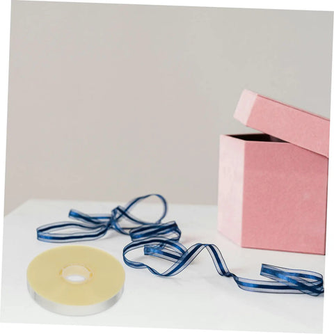 Heavy Duty Strapping Tie Roll For Easy Bundling And Shipping next to a pink box with a ribbon, transparent packing strap visible