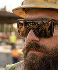 ANSI Z87+ Safety Sunglasses Packing Polarized Lenses For Work, Surf, And PPE. User outdoors with construction backdrop.
