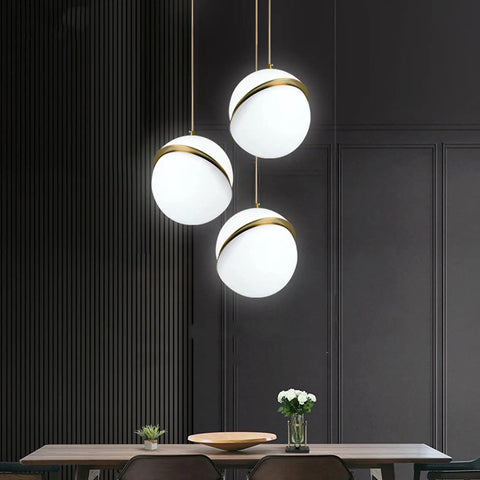 Three Acrylic Globe Pendant Lights With Irregular Hanging Design For Dining Room And Living Room Adjustable Cable 110 To 140 Volt UL Certified Includes Gold Ceiling Mount And Hardware For A Sleek Modern Vibe, with three globes hanging over a dining table.