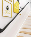 Black industrial style handrail on stairs with wall art decor behind, providing safety and aesthetic appeal.