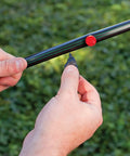 Hands connecting Pro Grade One-Half Inch Drip Irrigation Distribution Tubing Fifty Foot Roll In Black in garden setting.