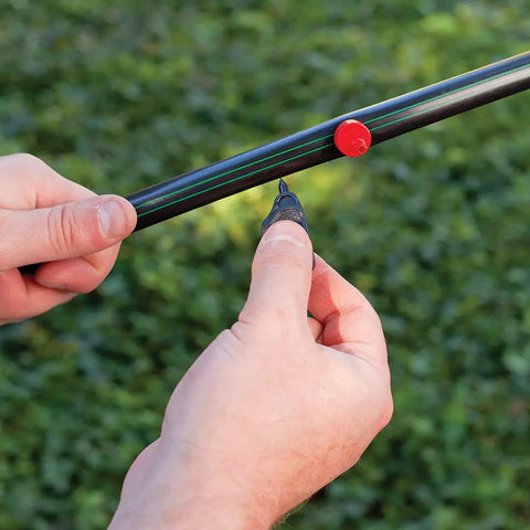 Hands connecting Pro Grade One-Half Inch Drip Irrigation Distribution Tubing Fifty Foot Roll In Black in garden setting.
