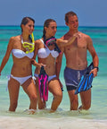 Three beachgoers holding Freedom Tri-Quest Scuba Diving Mask M-3001 in ocean green near the sea