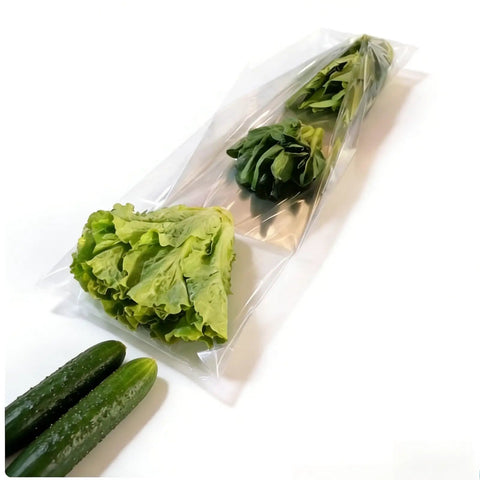 Compact Horizontal Flow Wrapper Shrink Wrap Machine 50 To 80 Pieces Per Minute wrapping fresh lettuce and greens in clear film.