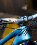 Close-up of blue bike with Full On Mountain Bike Handlebar, 31.8mm clamp, 785mm wide, 30mm rise beefy alloy riser bar, black finish.