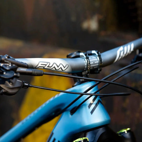 Close-up of blue bike with Full On Mountain Bike Handlebar, 31.8mm clamp, 785mm wide, 30mm rise beefy alloy riser bar, black finish.