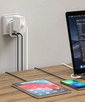 Laptop, tablet, and phone charging via Type G Travel Plug Adapter With 2 USB Ports And 1 AC Outlet For US To UK England Ireland Scotland Hong Kong Kenya Dubai And More Your Go To Travel Charger Converter For Global Trips And Home Use plugged into wall socket.