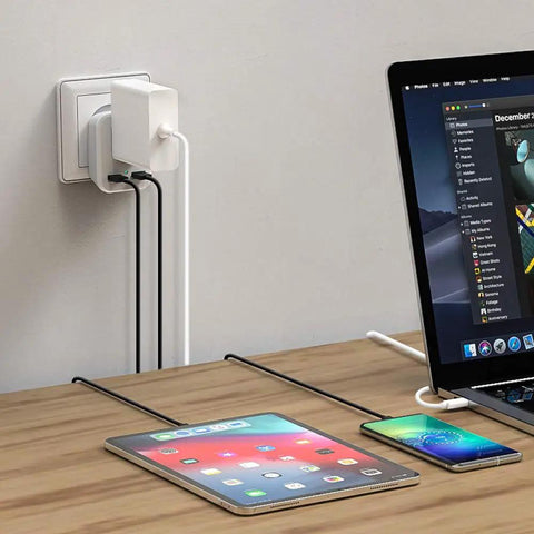 Laptop, tablet, and phone charging via Type G Travel Plug Adapter With 2 USB Ports And 1 AC Outlet For US To UK England Ireland Scotland Hong Kong Kenya Dubai And More Your Go To Travel Charger Converter For Global Trips And Home Use plugged into wall socket.