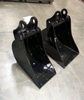 Two black buckets for Beast Workhorse 3 Point Hitch Backhoe For Tractors With 9 ft Digging Depth 180 Degree Swing Two Buckets 10 Inch And 15 Inch Cat 1 And Cat 2 Linkage Hydraulic Thumb Upgrade New In Box on concrete floor