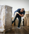 Person using Industrial Strength 18 Inch Stretch Film Wrap Roll Set For Moving And Packing, 1500 Feet Per Roll on furniture.
