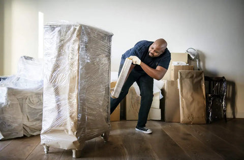 Person using Industrial Strength 18 Inch Stretch Film Wrap Roll Set For Moving And Packing, 1500 Feet Per Roll on furniture.
