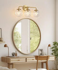 Three Light Vanity Wall Sconce Over Mirror In Matte Gold Finish With Transparent Glass Ball Shade, up in home office