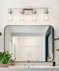 Four Light Brushed Nickel Bathroom Vanity Light With Clear Glass Shades above mirror in modern bathroom setting
