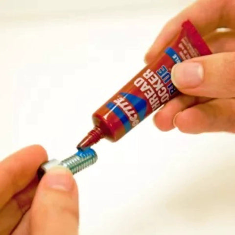 Application of Tough As Nails Medium Strength Threadlocker Glue on a bolt from a red tube for secure fastening.