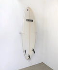 Heavy Duty Vertical Surfboard Wall Mount Rack Made From Crystal Clear Acrylic displaying a surfboard on a white wall.