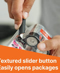 Close-up view of a black Slice 10513 pen cutter with textured slider button cutting clear packaging