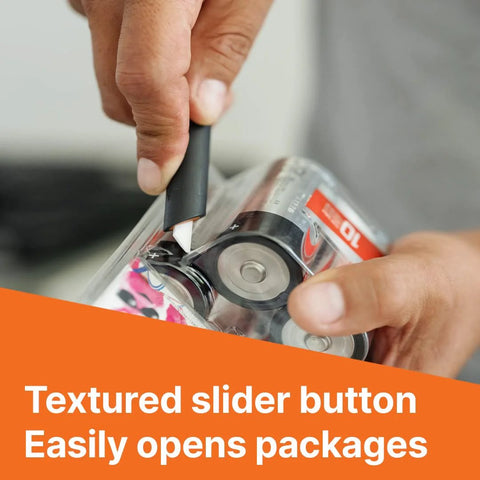 Close-up view of a black Slice 10513 pen cutter with textured slider button cutting clear packaging