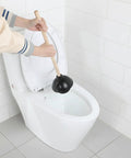 Person using a Six Pack Heavy Duty Black Toilet Plungers Featuring Solid Wood Handles And Beefy Rubber Cups on a toilet