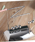 Z Shape Newtons Cradle Desk Toy For Home Office Decor with five silver balls on wooden desk, showcasing energy balance.