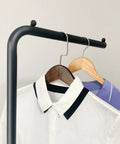 Close-up of Matte Black Metal Coat Rack Dope Modern Clothing Tree With Heavy Slate Base holding shirts on hangers