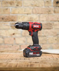 PWR CORE 20 Brushless 20V Cordless Hammer Drill Kit on table, showing drill bit and compact design against brick wall background.