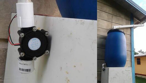 Portable Micro Hydro Water Turbine Generator For DIY Power Up 5V To 80V DC Output 10W Charging LED Light And Radio Off Grid Ready Hydroelectric Power Kit For Emergency Backup installed on building with blue water barrel.