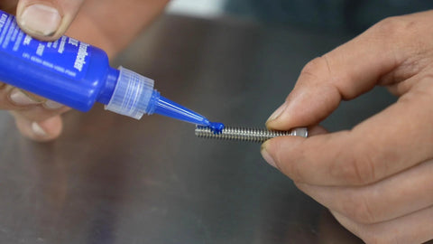 Permatex blue 6 ml medium-strength threadlocker applied to a metal threaded bolt
