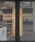 Solid Wood Push Pull Glass Door Handle For Hotels Shops And Homes Ash Wood Door Handle With Anti Corrosion Finish installed on glass doors in a modern interior.
