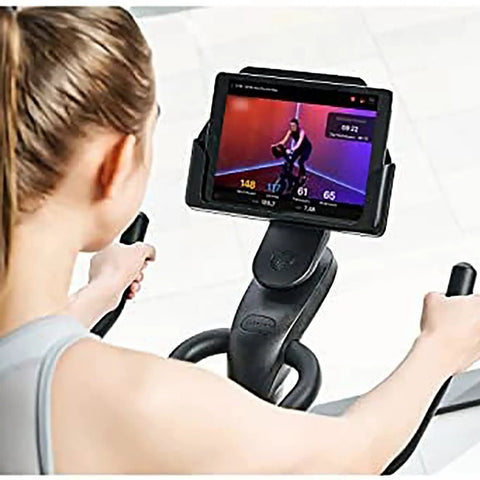 Person using Quiet Indoor Cycling Bike For Home Gym With Magnetic Resistance And Belt Drive Stable Steel Frame Adjustable Cage Pedals Smooth Low Impact Cardio Workout No Fuss Easy To Use And Store viewing virtual trainer on tablet