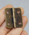 Person holding a 42 Piece Mini Hinge Set in Antique Bronze Finish, heavy duty cast iron, rounded corners, 30x27mm.