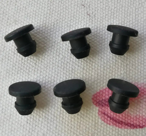 Black Silicone Rubber Washers Kit For Home Repairs, Durable Snap-On Hole Plugs And Gasket Seals That Fit Cracks Perfectly To Stop Leaks Fast. Black silicone snap-on hole plugs shown on fabric, six-piece rubber gasket seals for home repairs.