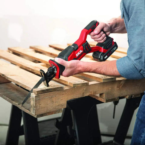 Person using a reciprocating saw from 4 Tool Power Kit With 20V Cordless Drill Driver Impact Driver Reciprocating Saw And LED Spotlight