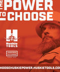 Worker in hard hat with 'The Power to Choose' Husky Tools advertisement backdrop.