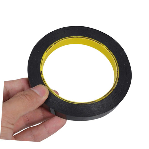 Hand holding one roll blackout tape for windows that blocks LED light and dims screens with heavy duty adhesive window covering.