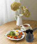 Table setting with Electric Turkish Coffee Maker 500ml Pot With Removable Handle, breakfast plate, and cup of tea