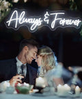 Couple embracing under Forever Neon Sign For Weddings And Parties, Cold White LED Wall Decor backdrop, romantic ambience.