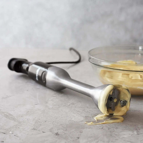 Level Up Your Kitchen Routine With The Control Grip Immersion Blender Anti Suction Tech Stops Splatters While You Blend Includes 42 Oz Jug Plus Whisk For Silky Smooth Soups And Creamy Mixes With Comfortable Trigger Handle In Brushed Stainless Steel, close-up with creamy mixture.